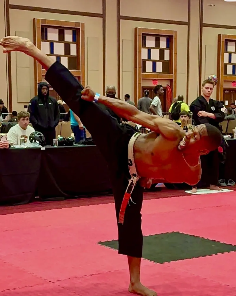 Kevin Thompson Jr. throwing a high kick at a tournament